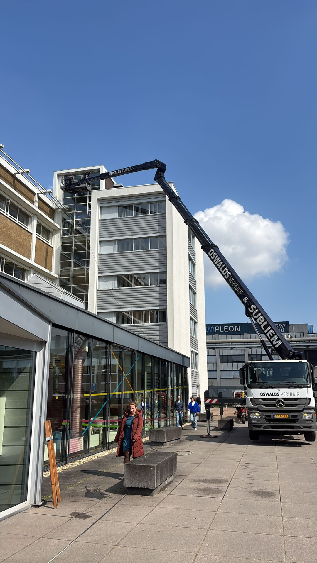 Autohoogwerker van Oswalds Verhuur & Subliem aan het werk bij een kantoorpand